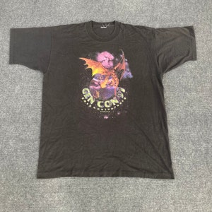 May include: Black t-shirt with a graphic of a dragon flying in front of a planet and stars. The text "Gen Con 97 30th Anniversary" is printed on the shirt.