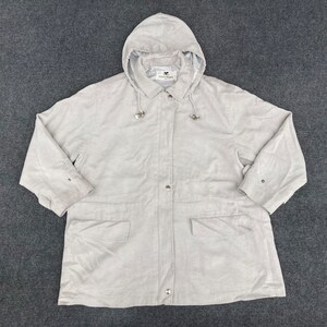 Puede incluir: Una chaqueta gris claro con capucha, cierre de cremallera y capucha con cordón. La chaqueta tiene dos bolsillos delanteros y una etiqueta de marca que dice "Country Road".