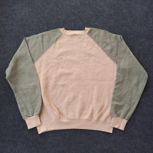 Op de afbeelding: Een longsleeve sweatshirt met een roze body en groene raglanmouwen. Het sweatshirt heeft een ronde hals.