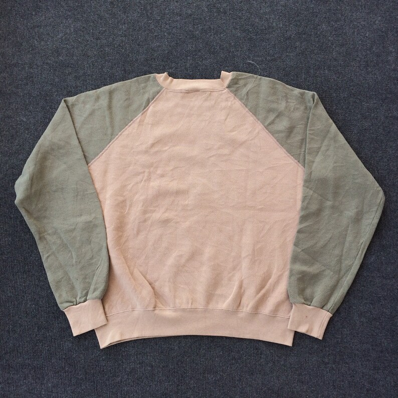 Op de afbeelding: Een longsleeve sweatshirt met een roze body en groene raglanmouwen. Het sweatshirt heeft een ronde hals.
