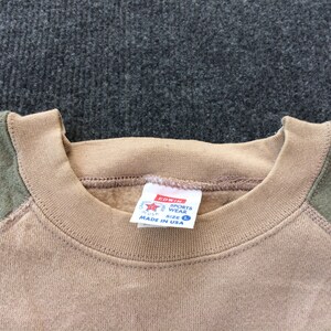 Op de afbeelding: Tan sweatshirt met groene raglanmouwen. De sweatshirt heeft een ronde hals en een label met de tekst "Edwin Sports Wear Maat L Gemaakt in de VS".