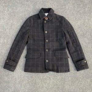 May include: A black and white checked jacket with a button-up front and a collar. The jacket has two pockets on the front and a flap on each cuff.