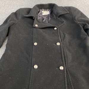 May include: A black double-breasted coat with large silver buttons. The coat has a classic design with a notched collar and a tailored fit. The coat is made of a wool-like material and appears to be in good condition.