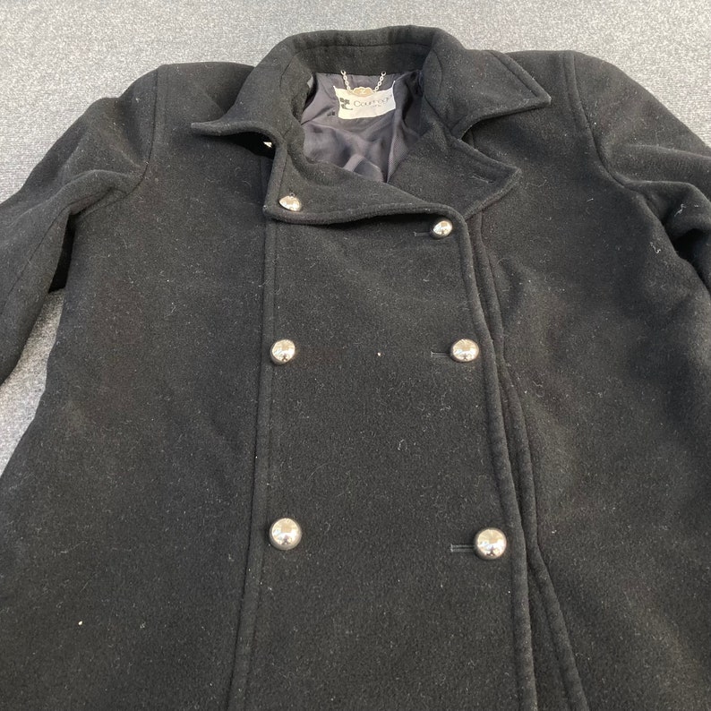 May include: A black double-breasted coat with large silver buttons. The coat has a classic design with a notched collar and a tailored fit. The coat is made of a wool-like material and appears to be in good condition.