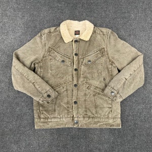 May include: A brown corduroy jacket with a sherpa collar and multiple pockets. The jacket has a button closure and a faded look.