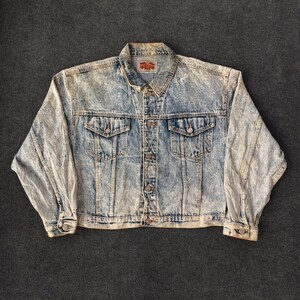 May include: A light blue denim jacket with a faded acid wash effect. The jacket has a button closure, two chest pockets, and two front pockets. The label on the jacket reads "Old Navy".
