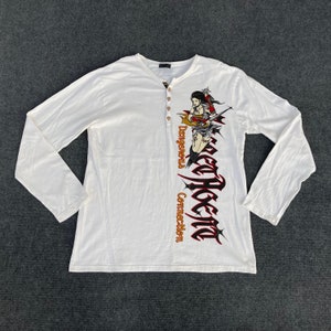May include: White long-sleeve shirt with a graphic print of a woman holding a sword. The text "Secret Holic" is printed vertically on the shirt with the words "Dangerous Connection" printed below it.