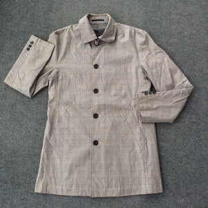 May include: A brown and beige checked long-sleeved jacket with a button-up front and four buttons. The jacket has two pockets on the front and a collar.