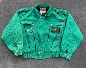 May include: A green jacket with black trim and a zippered pocket. The jacket has a Formula 1 patch on the left chest with the text "Formula 1" and "Privex Original".