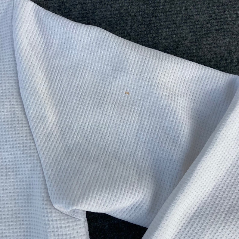 May include: White waffle knit fabric with a small brown stain.