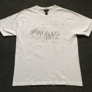 May include: White short-sleeved t-shirt with a grey print of "DKNY JEANS ESTABLISHED 1989" on the front.
