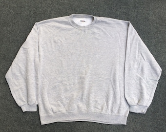May include: A gray sweatshirt with a crew neck and long sleeves. The sweatshirt has a small tag on the front that says "Fruit of the Loom".