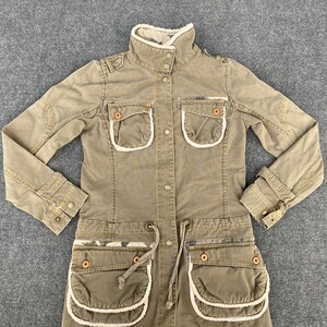May include: A long-sleeved, brown, utility-style jacket with a sherpa lining. The jacket has multiple pockets with white trim and a drawstring waist.