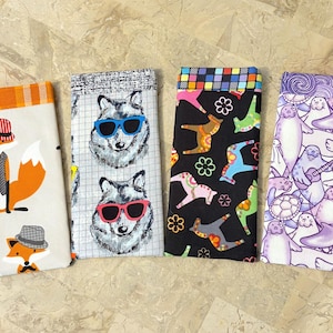 May include: Four fabric cases with unique patterns. One features foxes in outfits, another has wolf faces with sunglasses, a third showcases colorful horse-like figures, and the last displays seals with musical instruments.