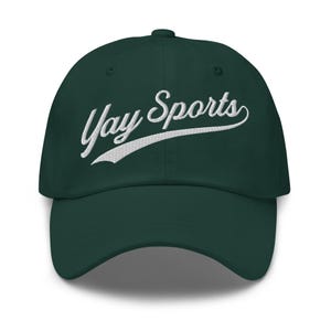 May include: A dark green baseball cap featuring the embroidered text "Yay Sports" in white script. The cap has a curved peak and a button on top. A classic, casual accessory.