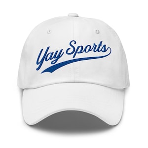 May include: White baseball cap featuring the blue text "Yay Sports" in a script font. The cap has a curved peak and a button at the crown. A sporty accessory for casual wear.