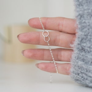 May include: A silver chain bracelet with two interlocking circles.