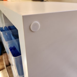 Peut inclure: Armoire blanche avec un pare-chocs en plastique blanc sur le coin inférieur.