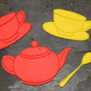 May include: A set of red and yellow cookie cutters shaped like a teapot, two teacups, and a spoon. The cutters are made of plastic and are ideal for making biscuits or other treats.