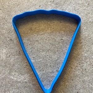May include: A blue plastic cookie cutter shaped like a slice of pizza.