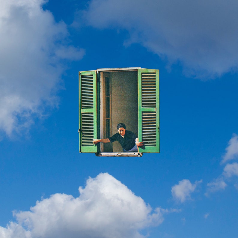 Op de afbeelding: Een persoon leunt uit een groen raamkozijn tegen een helderblauwe lucht met pluizige witte wolken. Het raam heeft open groene luiken. De persoon draagt een zwart shirt.