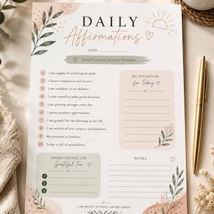 May include: A daily affirmations planner sheet featuring a list of ten positive statements, a section for daily intentions, a gratitude list, and a notes area. The design includes soft peach and sage green watercolor accents, botanical illustrations, and a sun icon.