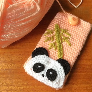 May include: A handmade peach-colored crochet phone case with a panda face design. The case features a green bamboo design and a button closure. A ball of peach yarn and a green crochet hook are also visible.