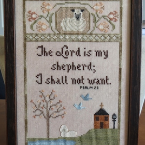 Puede incluir: Bordado de punto de cruz con un cordero blanco, un árbol, una casita y pájaros. El texto dice "El Señor es mi pastor, nada me faltará. Salmo 23."
