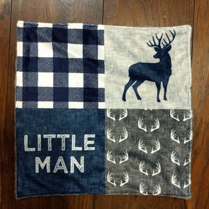 May include: A blue and white checkered fabric square, a blue denim square with the text "LITTLE MAN" in white, a white deer silhouette on a gray fabric square, and a gray fabric square with a white antler pattern.