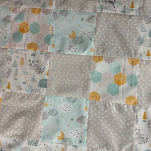 May include: A patchwork quilt with a woodland theme. The quilt is made of various fabrics with different patterns, including stars, clouds, and geometric shapes. The quilt features a variety of woodland animals, including raccoons, owls, and squirrels.