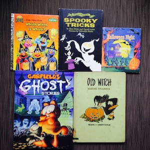 May include: A collection of vintage Halloween-themed children's books. Titles include "Which Witch Is Which?", "Spooky Tricks", "Halloween Night", "Garfield's Ghost Stories", and "Old Witch Rescues Halloween". The books feature colorful illustrations and spooky themes.