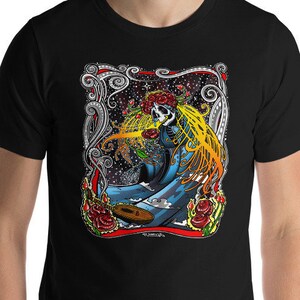 May include: Black t-shirt with a colorful graphic print of a skull with a crown of roses and a blue and yellow figure. The figure is holding a paintbrush and a paint palette.