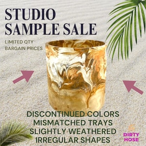 May include: A cylindrical container with a marbled design in shades of brown, tan, and white. The text "STUDIO SAMPLE SALE" and other text are visible. The container has irregular shapes and is slightly weathered.