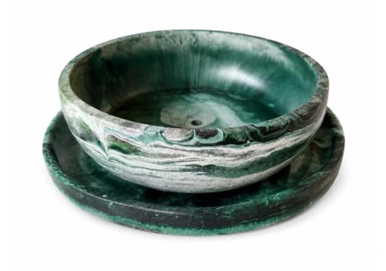 May include: A round bowl and matching saucer set featuring a marbled pattern in shades of deep forest green, emerald, and white. The bowl has a smooth, curved interior with a small circular drain hole at the base, while the saucer is flat.