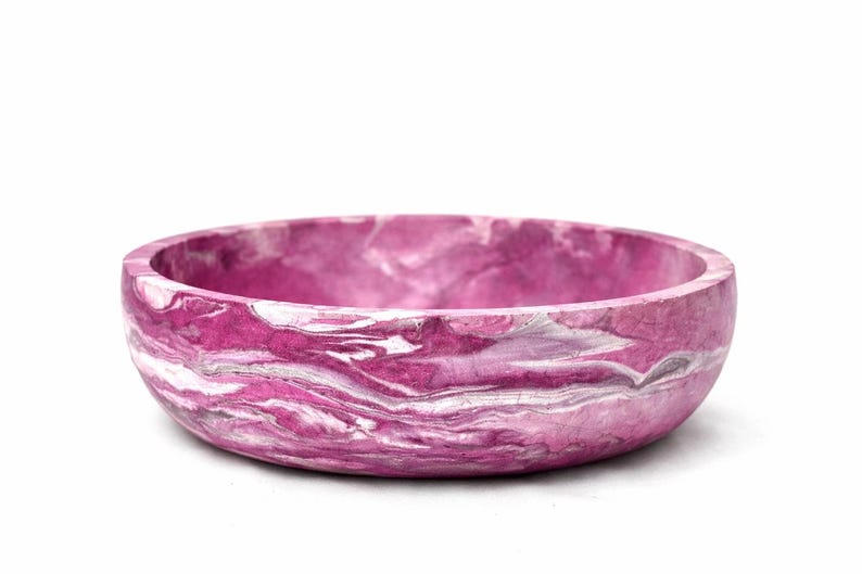 May include: A round bowl featuring a vibrant magenta and white marbled pattern throughout its surface. The bowl has a smooth, curved exterior and a wide, open top, showcasing a swirling, fluid design that blends deep pink tones with bright white.