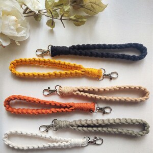 May include: Five different colored braided keychains with silver clasps. The keychains are in the colors black, yellow, beige, orange, and white.