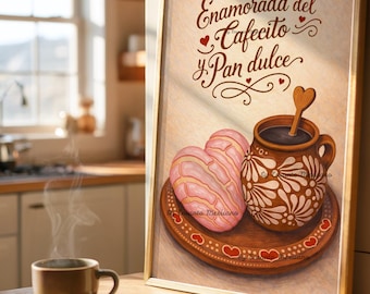 May include: A framed print featuring a cup of coffee, two heart-shaped pastries, and a decorative mug. The text "Enamorada del Cafecito y Pan dulce" is written in brown script. The print has a gold frame and is set on a wooden surface.