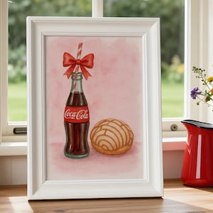 Könnte beinhalten: Ein gerahmter Aquarelldruck mit einer Coca-Cola-Flasche mit roter Schleife und einem Concha-Gebäck. Die Flasche hat ein rotes Etikett mit dem Coca-Cola-Logo. Der Hintergrund ist ein zartes Rosa. Der Druck ist in einem weißen Rahmen.