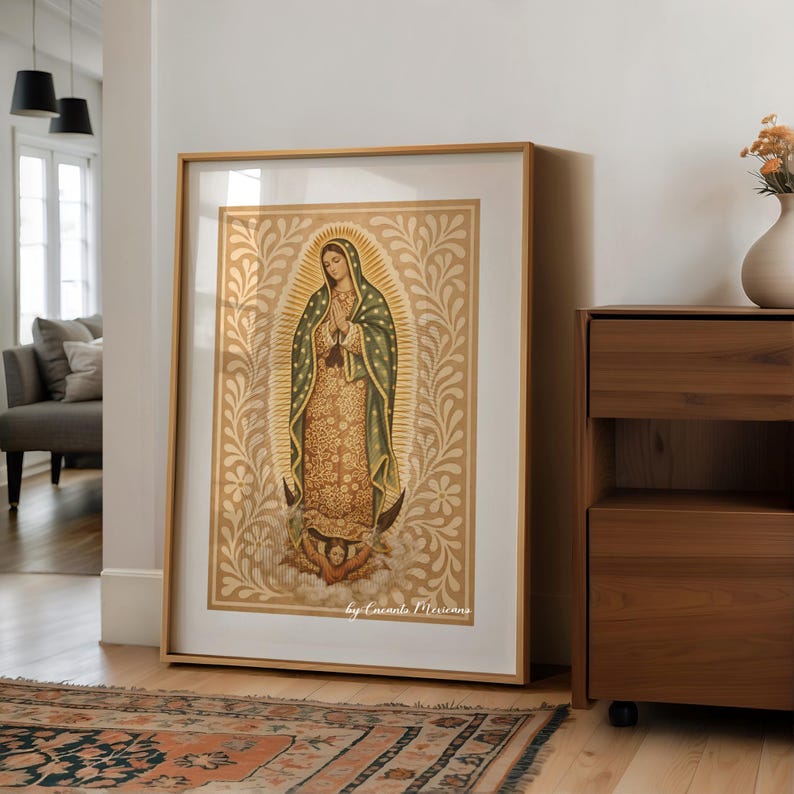 May include: Framed art print of Our Lady of Guadalupe. The artwork features a detailed depiction of the Virgin Mary with a gold halo and a green and gold robe. The print is set against a gold background with floral patterns and is framed in a light wood frame.