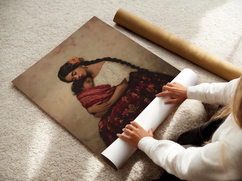 May include: A square art print featuring a painting of a person with long dark braided hair wearing a white top and a dark red floral skirt, holding a sleeping child wrapped in a red patterned cloth against a soft beige background.