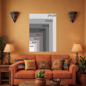 May include: A living room scene with an orange sofa, wooden coffee table, and colorful pillows. A framed print displays various size options, including 24x36 inches. The room is decorated with lamps, wall sconces, and a striped rug, creating a warm, inviting atmosphere.