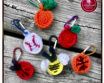 May include: A collection of colorful, crocheted keychains in various shapes, including a carrot, apple, baseball, ladybug, bee, and orange slice. Each keychain has a metal clip for easy attachment. The keychains are handmade and feature vibrant colors.