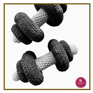 May include: Two crocheted dumbbells, one black and white and the other black and grey, are shown against a white background. The dumbbells are made of soft yarn and have a textured surface.