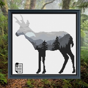 Puede incluir: Patrón de punto de cruz en blanco y negro de una silueta de ciervo con un paisaje de montaña en su interior. El patrón está en un marco negro con un icono de descarga PDF.