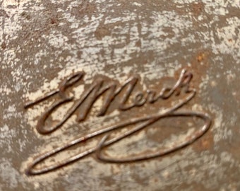 May include: Close-up of a metal surface with the inscription "E. Merck" in a cursive script.