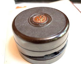 May include: A round, dark brown, bakelite doorbell button with a raised, circular, red and gold logo that reads "HARTLEY & CO."