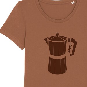 Könnte beinhalten: Braunes T-Shirt mit dunkelbrauner Grafik einer Espressokanne. Das Wort "ADDICT" ist auf dem Griff aufgedruckt. Das T-Shirt hat einen Rundhalsausschnitt und kurze Ärmel. Aus weichem Stoff.