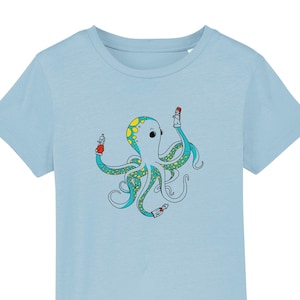 Könnte beinhalten: Ein hellblaues T-Shirt mit einem Cartoon-Oktopus, der Sprühdosen hält. Der Oktopus ist blau, grün und gelb mit schwarzen Umrissen.