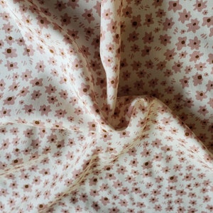 Pu&ograve; includere: Tessuto bianco con un motivo floreale rosa e marrone. Il tessuto &egrave; piegato e stropicciato.