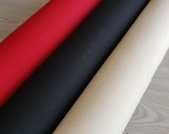 May include: Three rolls of fabric in red, black and cream colours. The fabric is smooth and appears to be a woven cotton.